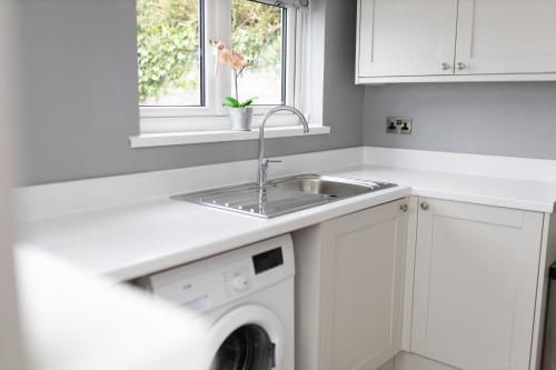 兰代洛Towy Snug的白色的厨房配有水槽和洗碗机