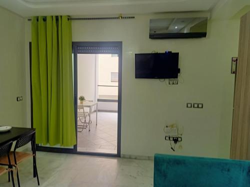 穆罕默迪耶Studio bord de mer Miramar的客厅配有绿色窗帘和电视