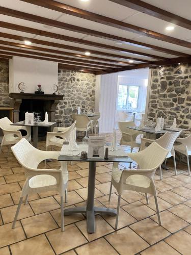 拉克河畔尚邦Hôtel-restaurant La bonne hôtesse的一间设有白色桌椅和石墙的餐厅