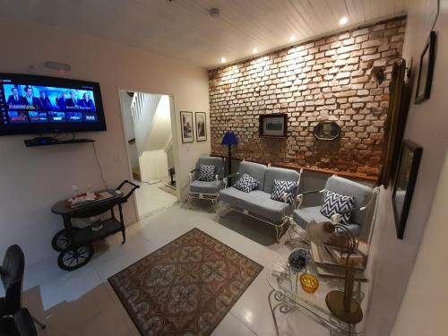 里奥格兰德Hostel Pousada Rheingantz Rio Grande的带沙发和电视的客厅以及砖墙。