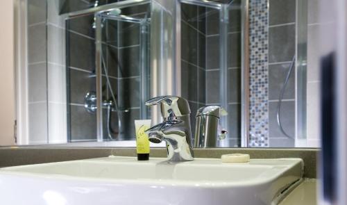 伦敦London Court Hotel的浴室水槽设有水龙头和镜子
