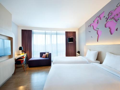 当格浪宜必思风格雅加达机场酒店的酒店客房设有两张床,墙上有一个世界。