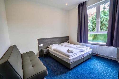 汉堡Hotel City Meetpoint的一间卧室配有一张床、一张沙发和一个窗口
