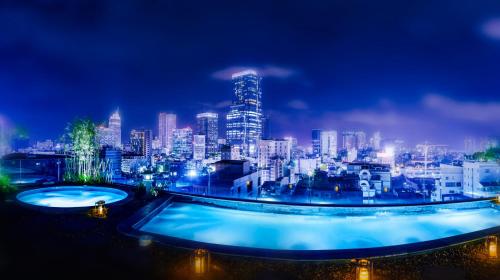 胡志明市Cochin Zen Hotel的城市天际线,晚上设有两个游泳池