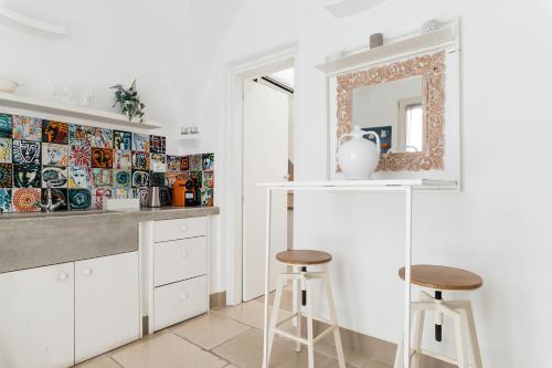 奥斯图尼Dimore del TEMPO PERS0 Prima Luce的厨房配有2张凳子和镜子