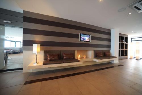 纳沙泰尔贝拉克财富品位酒店的大堂配有沙发和墙上的电视