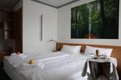 吕本瑙施普利瓦尔德贝斯特韦斯特酒店的一间卧室配有一张带毛巾的床和墙上的绘画
