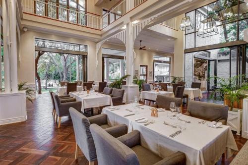 维多利亚瀑布Palm River Hotel的餐厅设有白色的桌椅和大窗户。