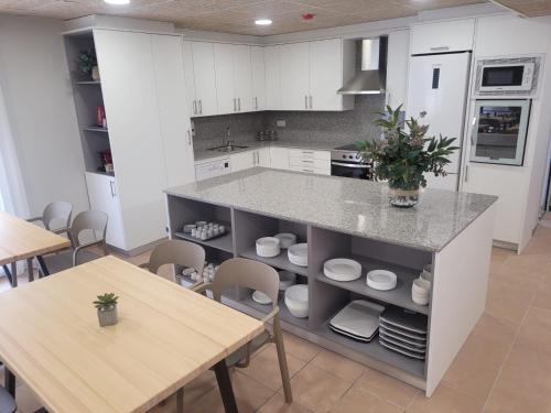 埃斯塔蒂特Malva Hostel的厨房配有白色橱柜、桌子和柜台。
