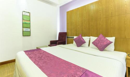 科泽科德Medora Hotel的配有紫色枕头的床的酒店客房