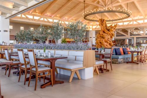 玛利亚Ikaros Beach, Luxury Resort & Spa - Adults Only的一间带桌椅和吊灯的餐厅