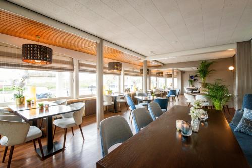 海边的艾格蒙特瓦西斯特拉德酒店的餐厅设有桌椅和窗户。