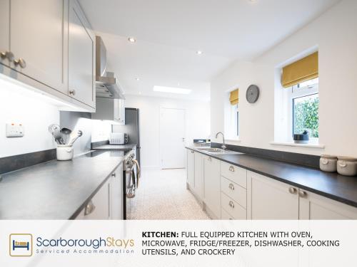 斯卡伯勒Scarborough Stays - Trafalgar Lodge - 4 bedroomed house - Free Parking的厨房配有白色橱柜和黑色台面