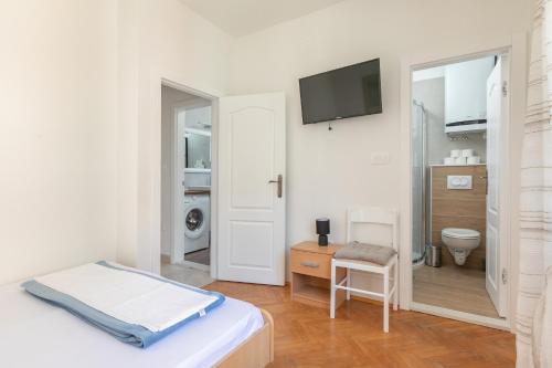 伯德古拉Apartman Ana Borić的白色卧室设有卫生间和墙上的电视。
