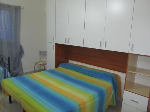 托雷奥沃Casa Salento Mare的卧室配有带白色橱柜的彩虹床。