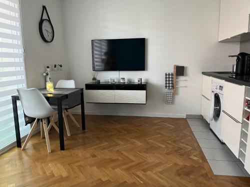德朗西Superbe studio lumineux haut de gamme tout confort的厨房配有桌子,墙上配有电视