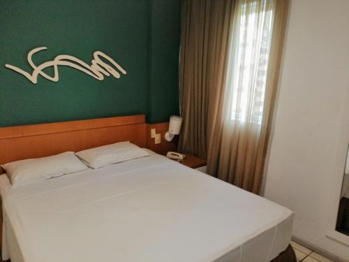 维多利亚Bristol Praia do Canto Apart Hotel的卧室配有白色的床和绿色的墙壁
