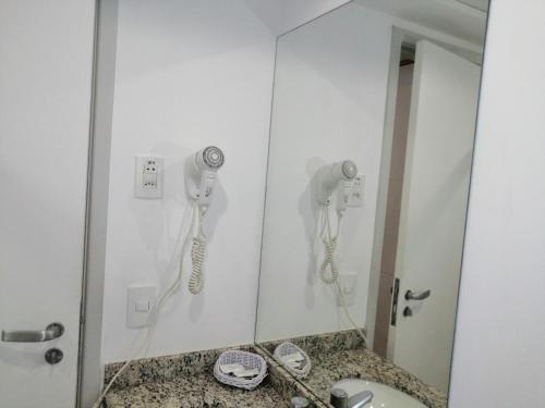 维多利亚Condomínio Bristol Praia do Canto Apart Hotel的浴室设有镜子,墙上设有电话