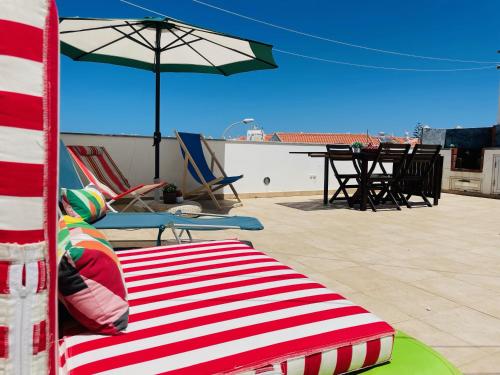 赞布热拉-杜马尔Sunset Beach House的庭院里配有红色和白色条纹的沙发和遮阳伞