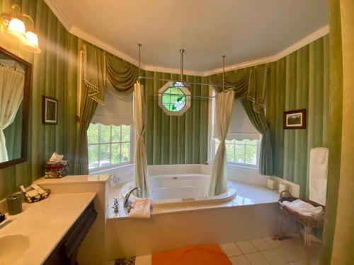 康威The Cypress Inn的浴室设有绿色窗帘和窗户浴缸