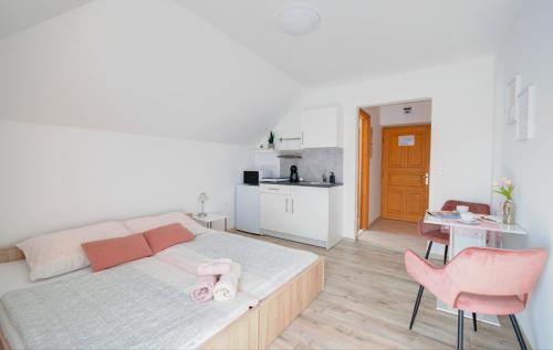 比克Villa Tara Bük的一间卧室配有一张带粉红色椅子的床和一间厨房