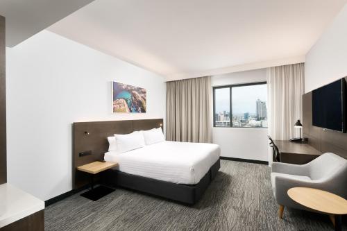 珀斯Holiday Inn West Perth, an IHG Hotel的配有一张床和一把椅子的酒店客房