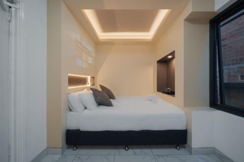 悉尼Cozy M Hotel的一间卧室配有一张带白色床单的床和一扇窗户。
