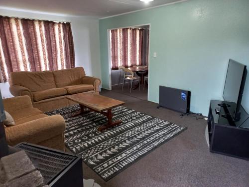 陶朗加Mount Budget Accommodation的带沙发、桌子和电视的客厅