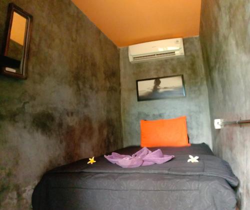 克拉玛斯Keramas Surf Hostel的小卧室配有带橙色枕头的床