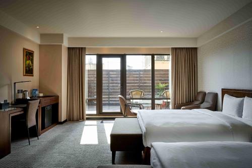 台中市来来商旅 的酒店客房设有一张床、一张书桌和一个阳台。