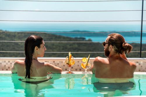 KlinciLuxury Holidays & Events - Villa Diva - Montenegro的两人坐在游泳池边喝饮料