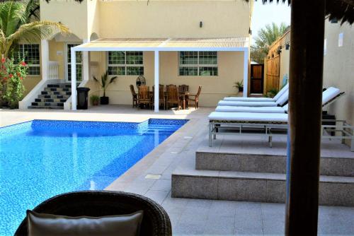 拉斯阿尔卡麦Dar 66 Pool Villa with Jacuzzi的一个带庭院和房子的游泳池