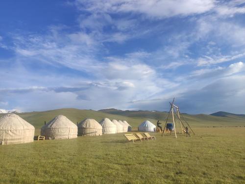 纳伦Yurt camp ALI-NUR at lake Song-Kol юрточный лагерь Али-Нур озеро Сон-Куль Сон-Куль Кыргызстан Нарын Kyrgyzstan Naryn的一群在有风车的田野中的圆顶