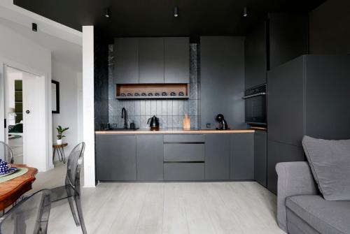 克拉科夫Partnerapart Rakowicka 14 Kamienica的厨房配有灰色的橱柜、桌子和沙发