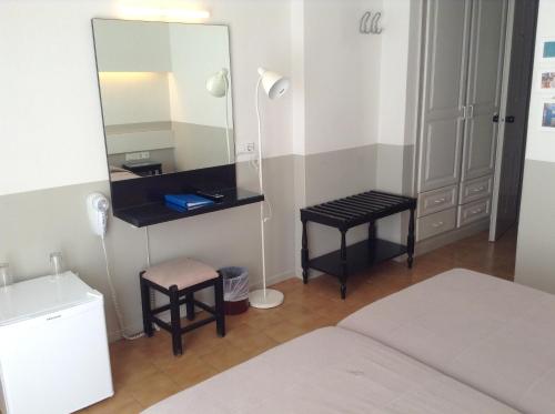 卡马利卡马里海滩酒店的一间带镜子、一张床和凳子的卧室