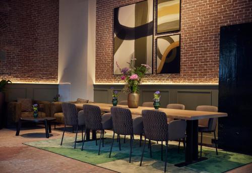 代尔夫特Hotel Arsenaal Delft的砖墙房里的桌椅