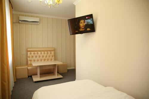 阿特劳美家园酒店的一间设有床铺和墙上电视的客房