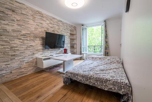 巴黎logement cosy et moderne proche de toute commodité的一间卧室设有砖墙、一张床和一张书桌