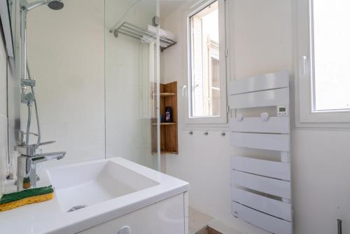 巴黎logement cosy et moderne proche de toute commodité的白色的浴室设有水槽和窗户。