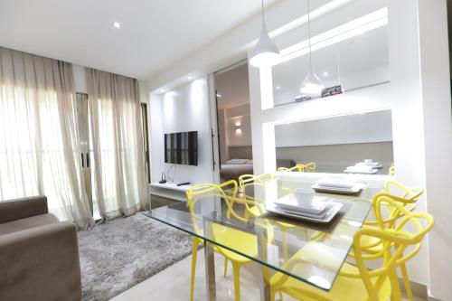 纳塔尔Premium Flat Ponta Negra Natal的一间设有玻璃桌和黄色椅子的用餐室
