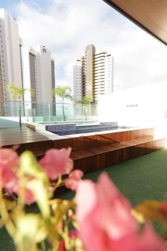纳塔尔Premium Flat Ponta Negra Natal的阳台享有粉红色的鲜花和城市美景。