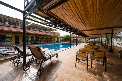 亚喀巴达纳潜水员村庄旅馆的一个带椅子的庭院和一个游泳池