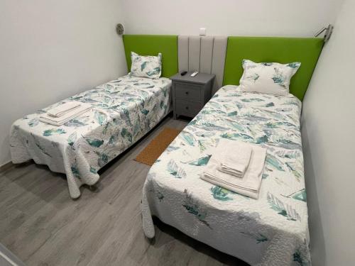 奥良利雅一室公寓酒店的配有绿色床头板的客房内的两张单人床
