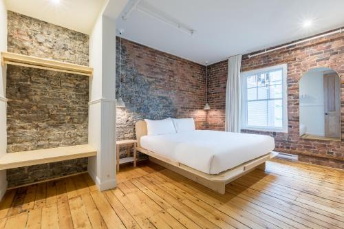 魁北克市La Maison des Lofts - Par les Lofts Vieux-Quebec的一间卧室设有一张床和砖墙