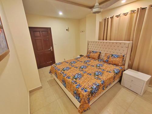 伊斯兰堡Family Friendly & Peaceful 3 Bed APT, Free Wifi的一间卧室配有一张带橙色棉被的床