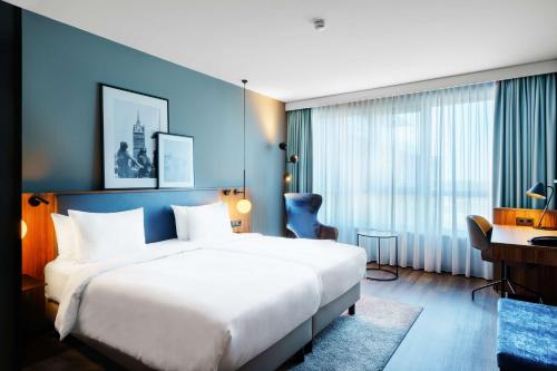 罗斯托克罗斯托克丽笙酒店的酒店客房设有一张白色大床和一张书桌