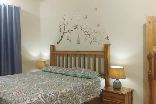 圣玛丽Chrisanns Hidden Cove 2 bedroom的卧室配有一张床,墙上挂着一幅树壁画