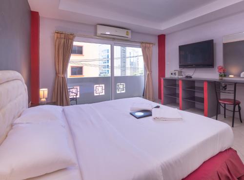 芭堤雅市中心罗宾雀巢旅馆及餐厅的卧室设有一张白色大床和一扇窗户。