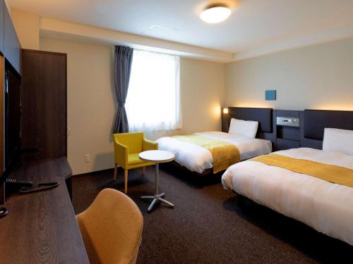 伊势市伊势舒适酒店的酒店客房设有两张床和一张桌子。