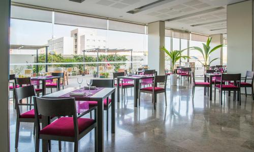 阿尔代阿瓦伦西亚克松斯酒店的餐厅设有粉红色的椅子和桌子以及窗户。